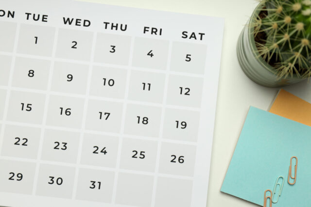 Calendar, sticky pad, and small cactus on desk